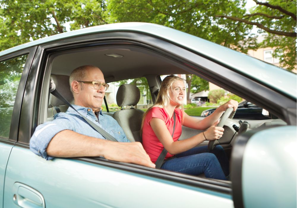 Teen driving vehicle with father.